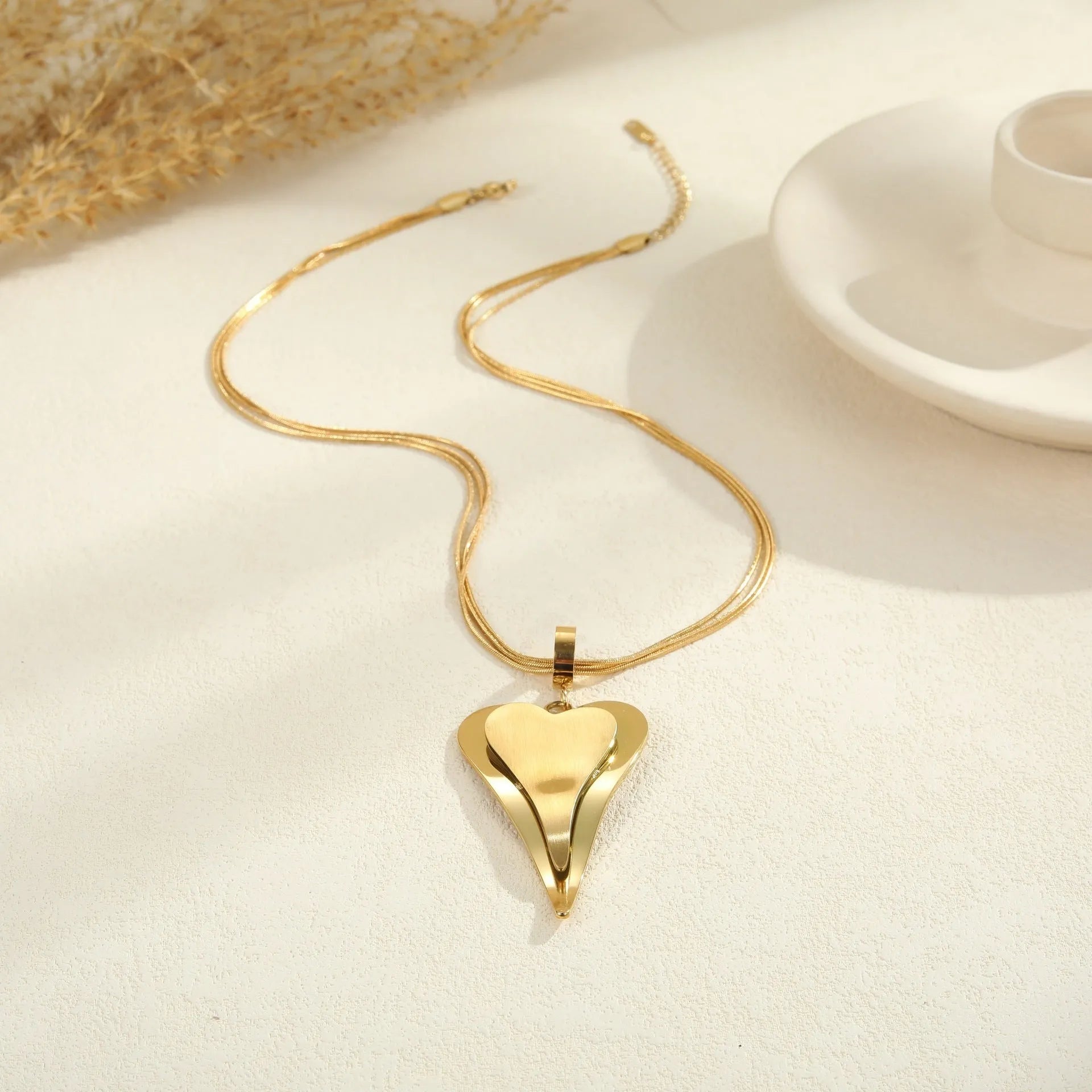 Women's stainless steel necklace with double heart geometric pendant on a snake bones chain in gold or steel finish.