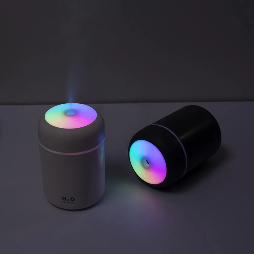 Pink USB portable humidifier with LED lights and water tank on wooden desk