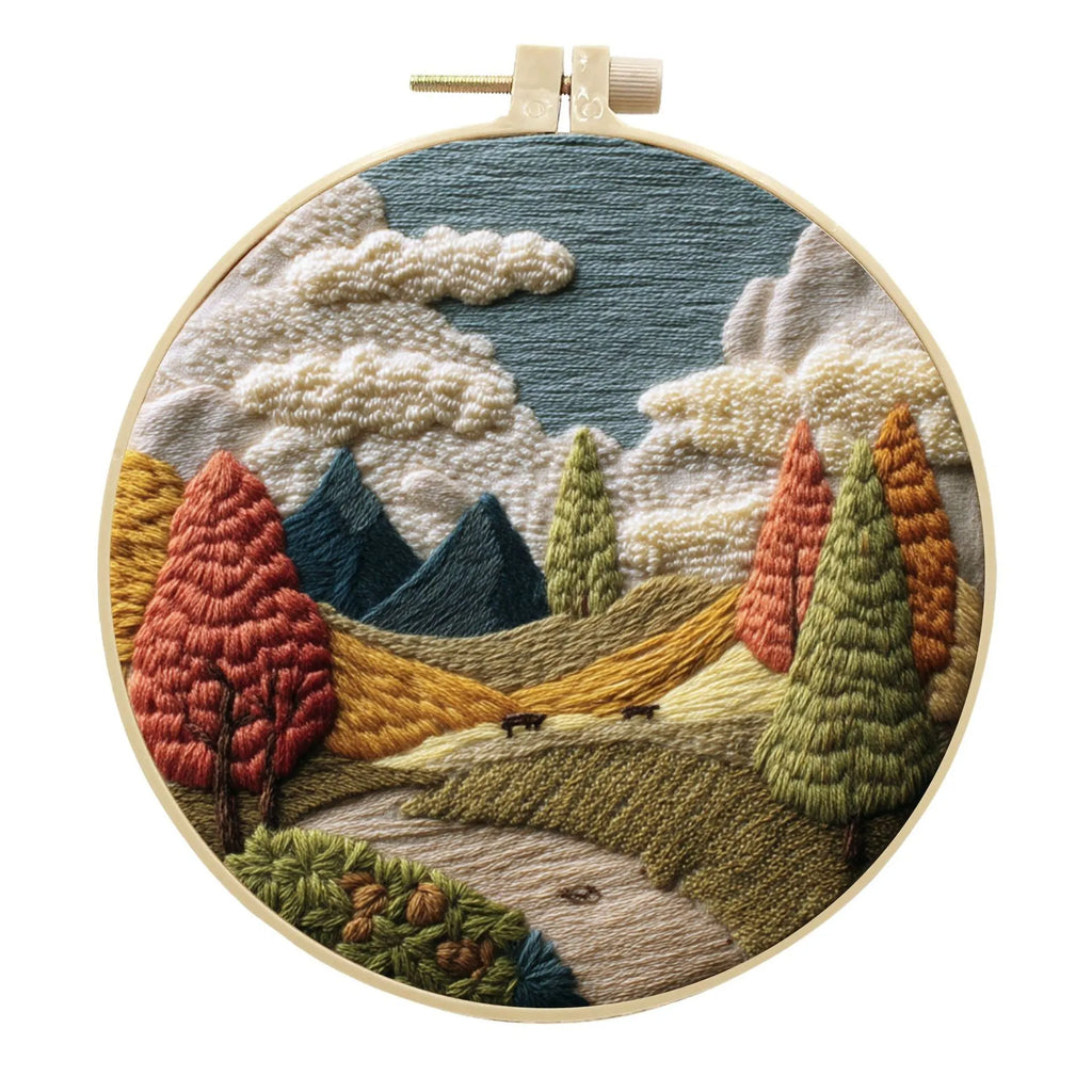 Landscape embroidery DIY kit with cotton fabric, printed pattern, embroidery frame, needles, and thread on wooden surface