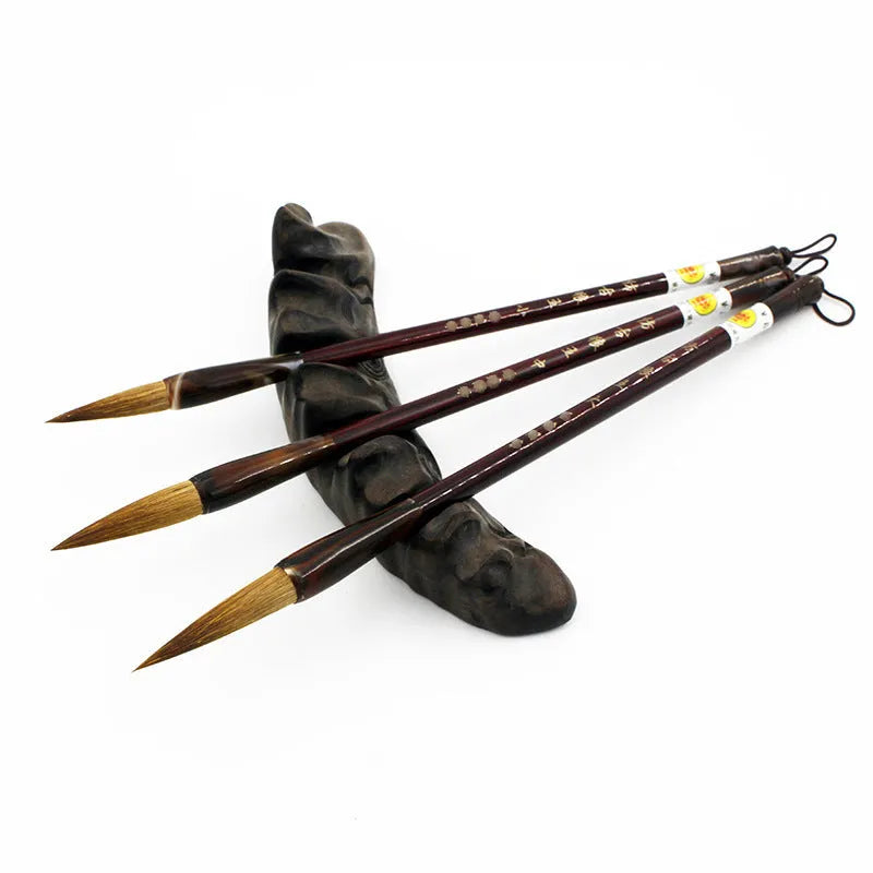 Set of three traditional Chinese calligraphy brushes with wolf hair bristles and steel ferrules in large, medium, and small sizes.
