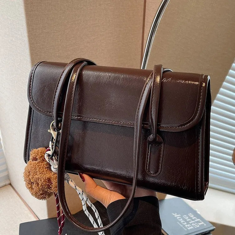 Brown women's PU leather crossbody shoulder bag with pendant, showing front view and adjustable double straps.