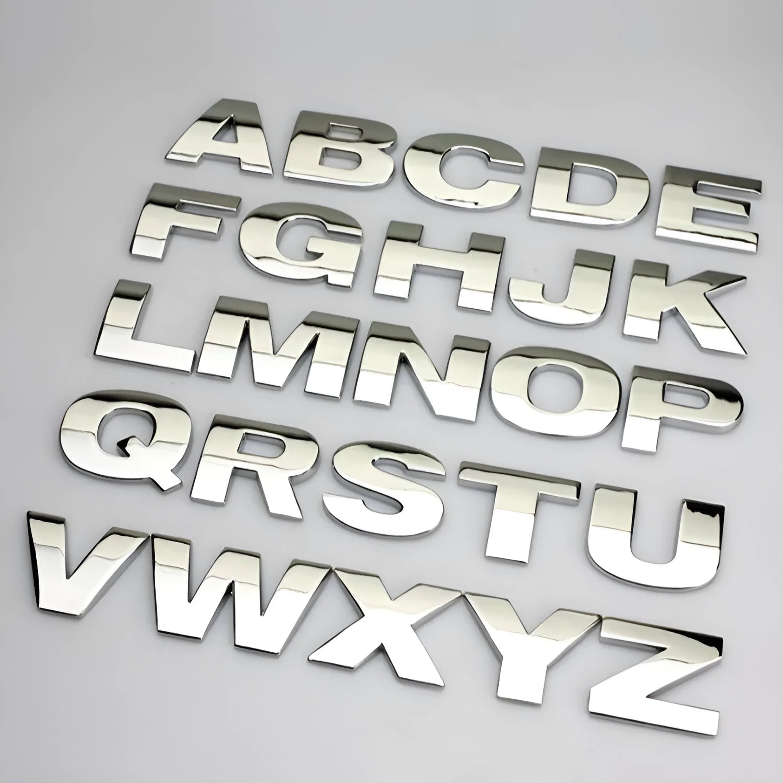 Close-up of a silver metal zinc alloy 3D letter 'A' car bumper sticker, approximately 2.5cm in size.