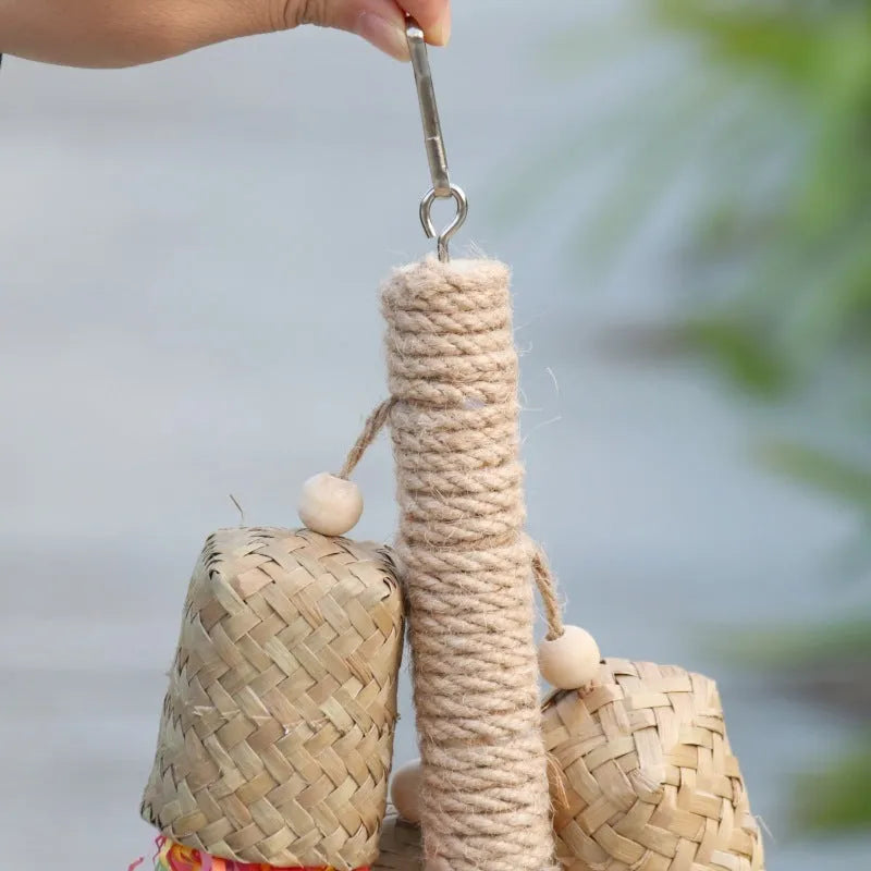 Wood and sisal rope parrot toy with colourful shredded paper hanging inside a bird cage.