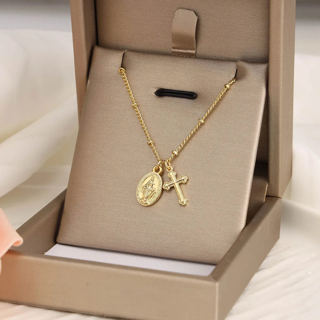 Gold geometric cross pendant necklace with Virgin Mary design on a chain.