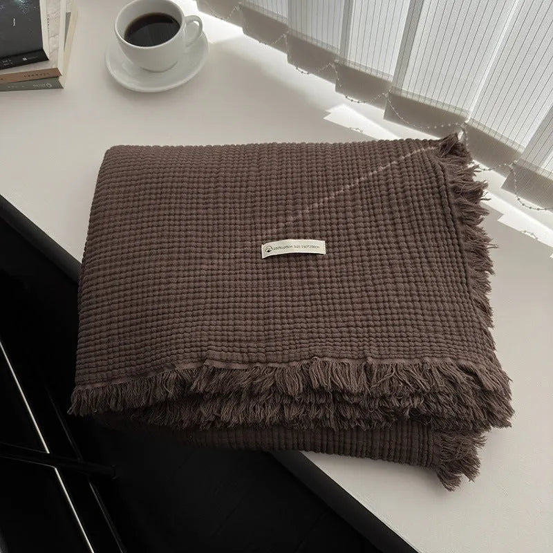 Four-layer gauze cotton blanket with tassel trim in navy blue colour laid flat.