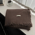 Four-layer gauze cotton blanket with tassel trim in navy blue colour laid flat.