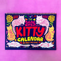 Cat themed wall calendar planner with daily tear-off sheets, showing photographic cat portraits and a clear date grid.