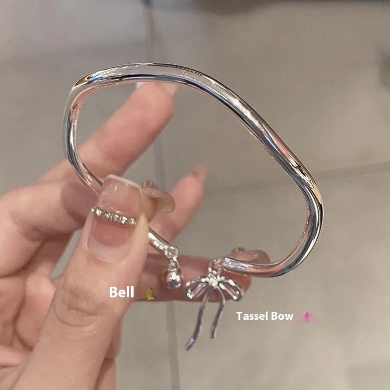 Silver bow bracelet with adjustable bell clasp on wrist, showing M1534 electroplated finish