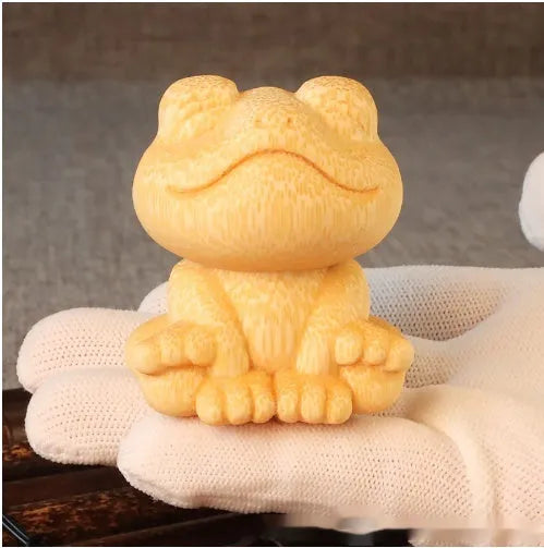 Solid bamboo carving ornament of a smiling cartoon frog, 5 cm tall.