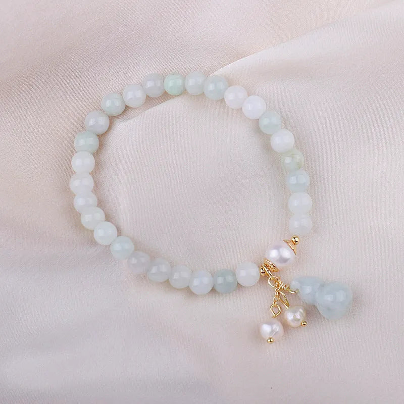 A handcrafted natural emerald jade bracelet with a detailed gourd charm, presented on a white background.