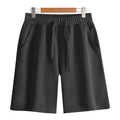 A pair of straight-cut cotton summer shorts in a neutral colour on a plain background.