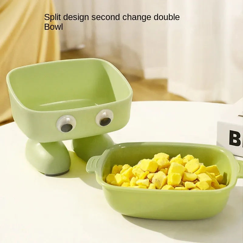 Green elevated cat bowl with 15-degree tilt, detachable inner dish, and cartoon robot design on a table.