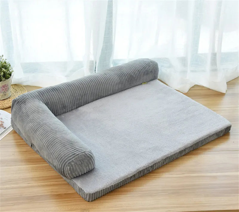 A corduroy dog sofa bed with raised sides, shown in a grey colour, placed on a wooden floor.