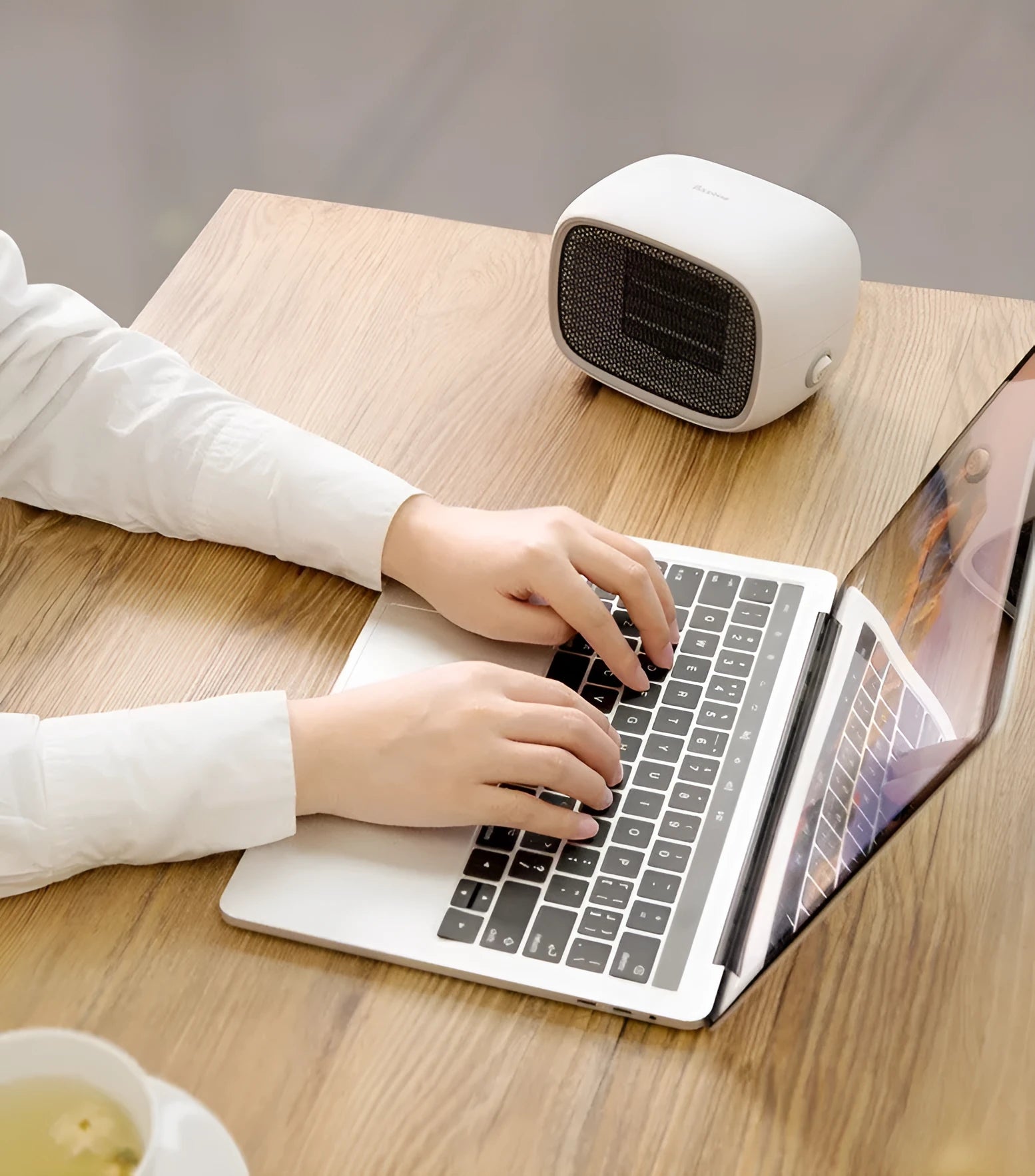 Mini green desktop heater with metal grille showing compact size on a wooden desk