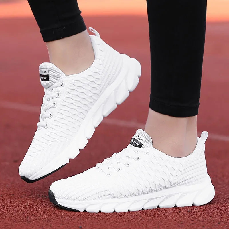 Women's running shoes in black, pink, or white with a breathable fly knit upper and durable outsole.