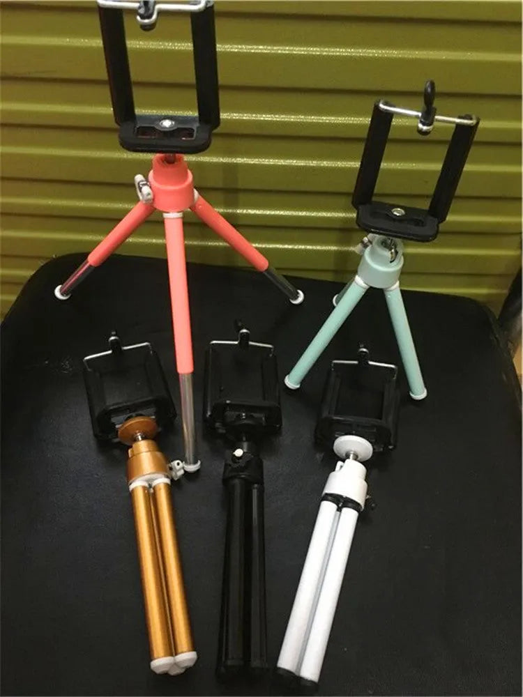Black adjustable metal desktop phone holder with a two-section bracket holding a smartphone.
