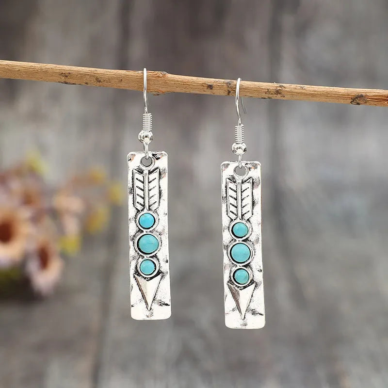 Silver geometric drop earrings with turquoise coloured inlays showing retro styling
