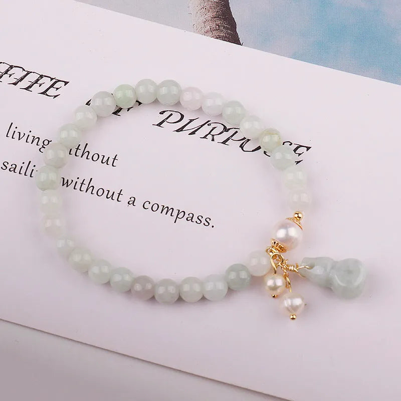 A handcrafted natural emerald jade bracelet with a detailed gourd charm, presented on a white background.