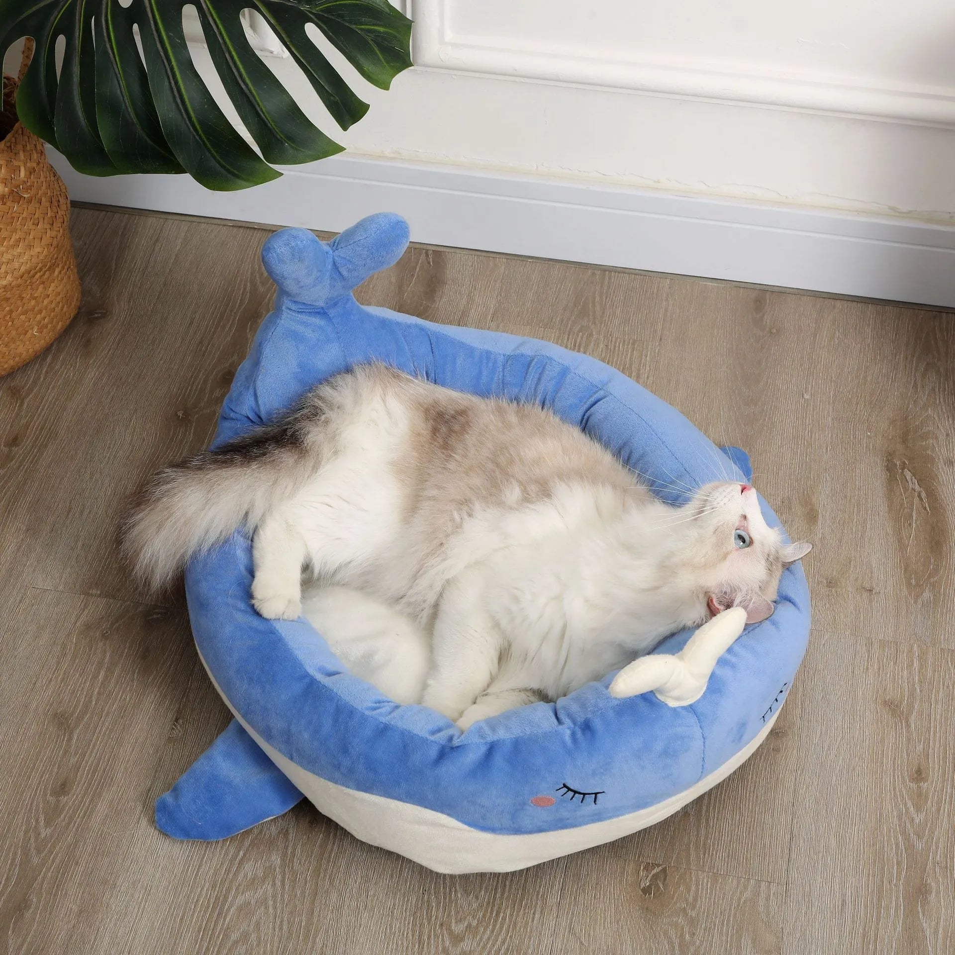 Blue duck-shaped fluffy pet bed for a small dog on a wooden floor.