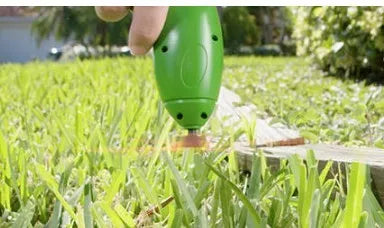 Cordless lawn trimmer with extension pole and protective shield on grass