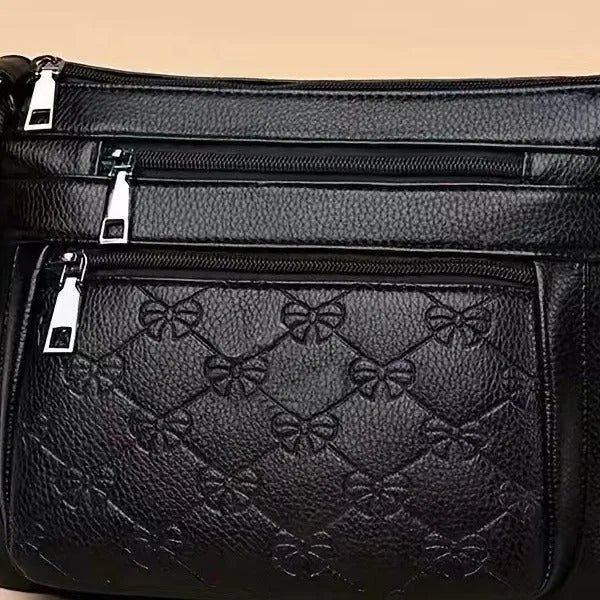 Black women's crossbody messenger bag with embossed texture and shoulder strap