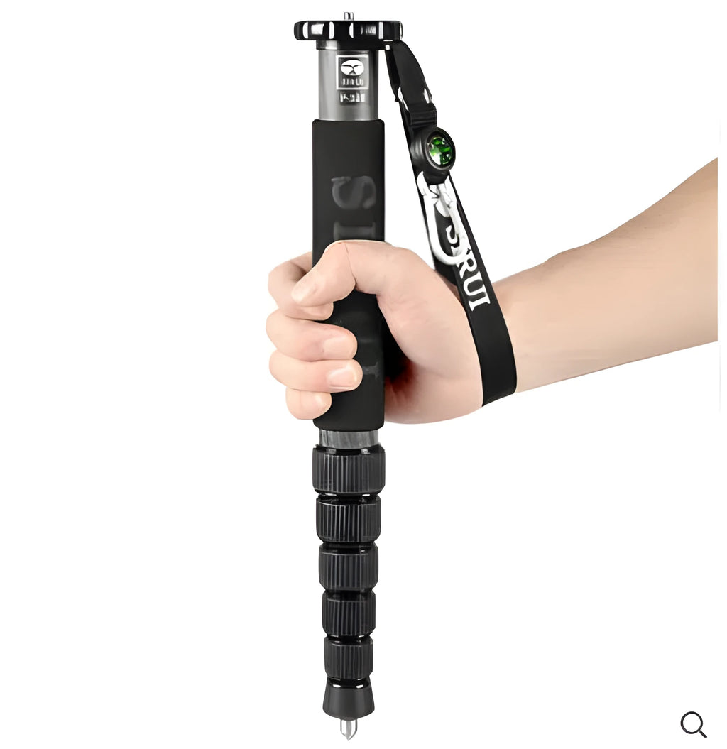 Black carbon fibre telescopic camera monopod fully extended next to a DSLR camera.