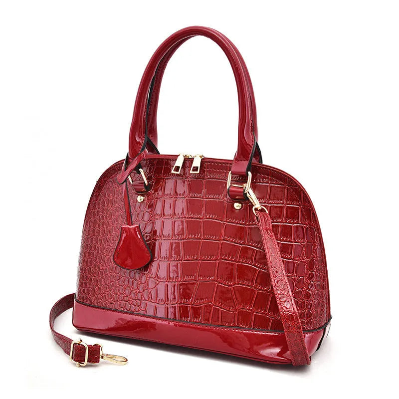 Large shiny PU leather crossbody shoulder bag in shell shape, showing black, red, and brown colour options