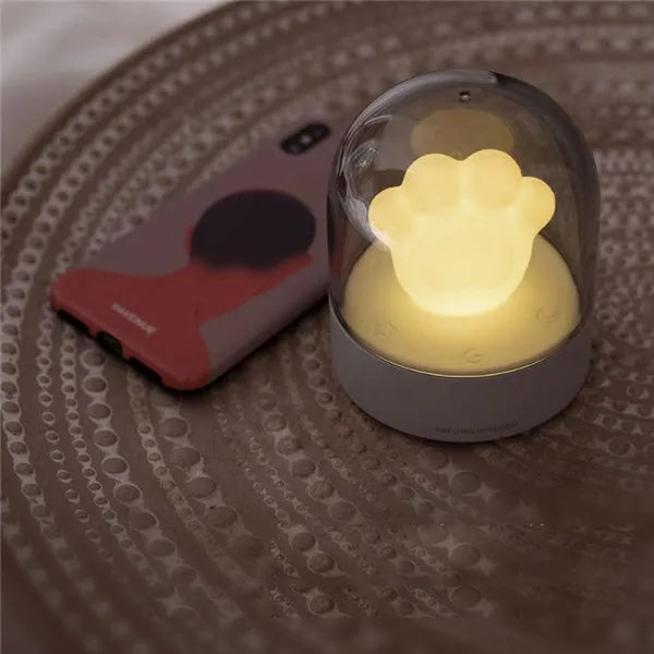 Pink cat paw shaped USB rechargeable night light with musical box function on wooden desktop
