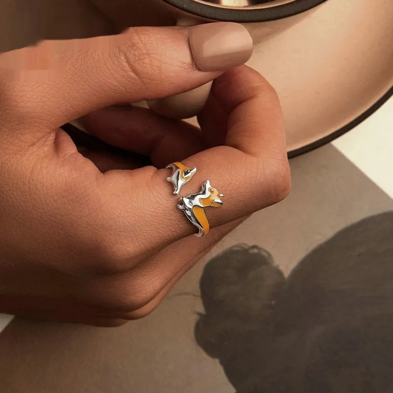 Close-up of a silver-coloured adjustable ring with a detailed cartoon corgi dog design on its face.