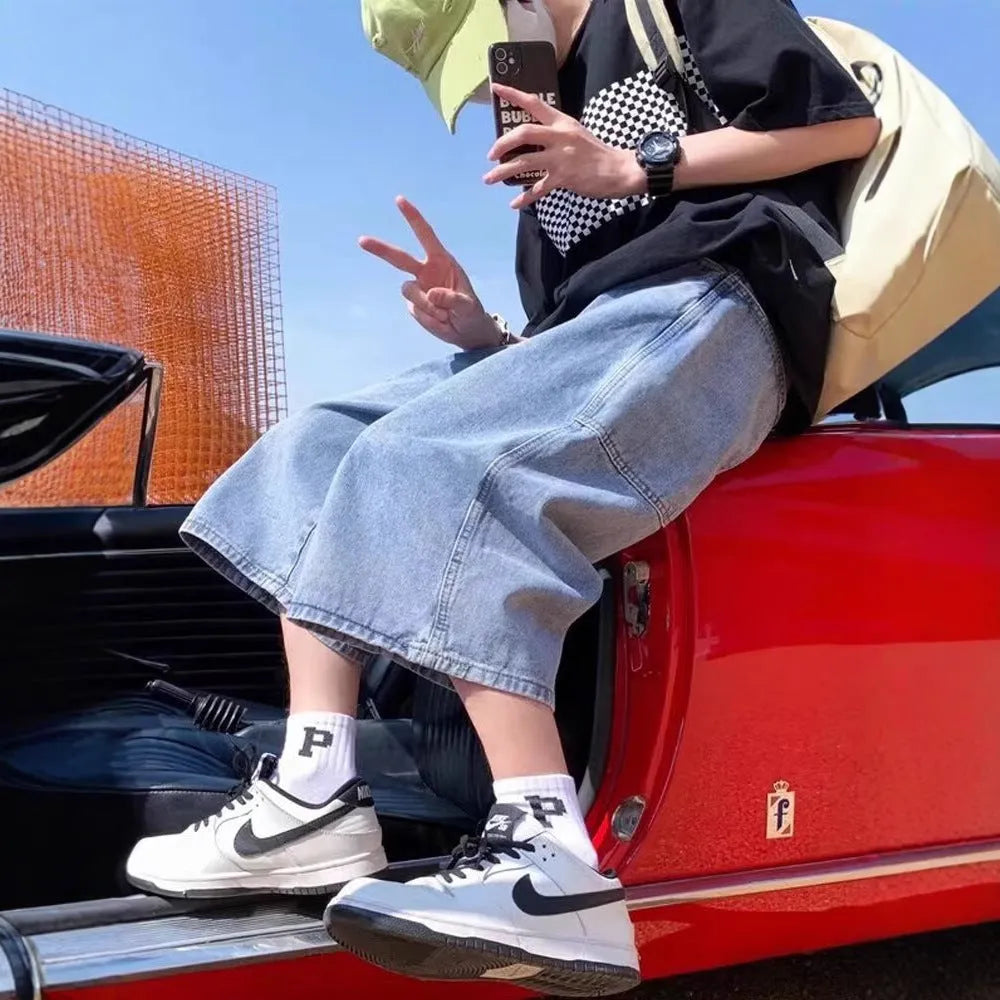 Man wearing blue high-waist straight-leg denim pirate shorts, showing cropped length and zipper fly