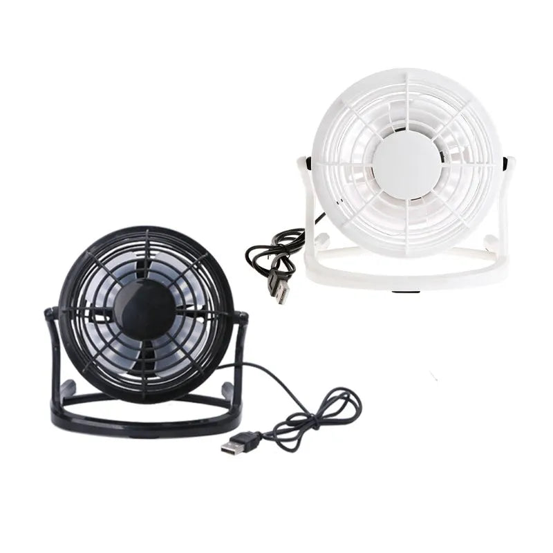 Compact black USB desk fan with adjustable tilt angle on a wooden desk next to a laptop