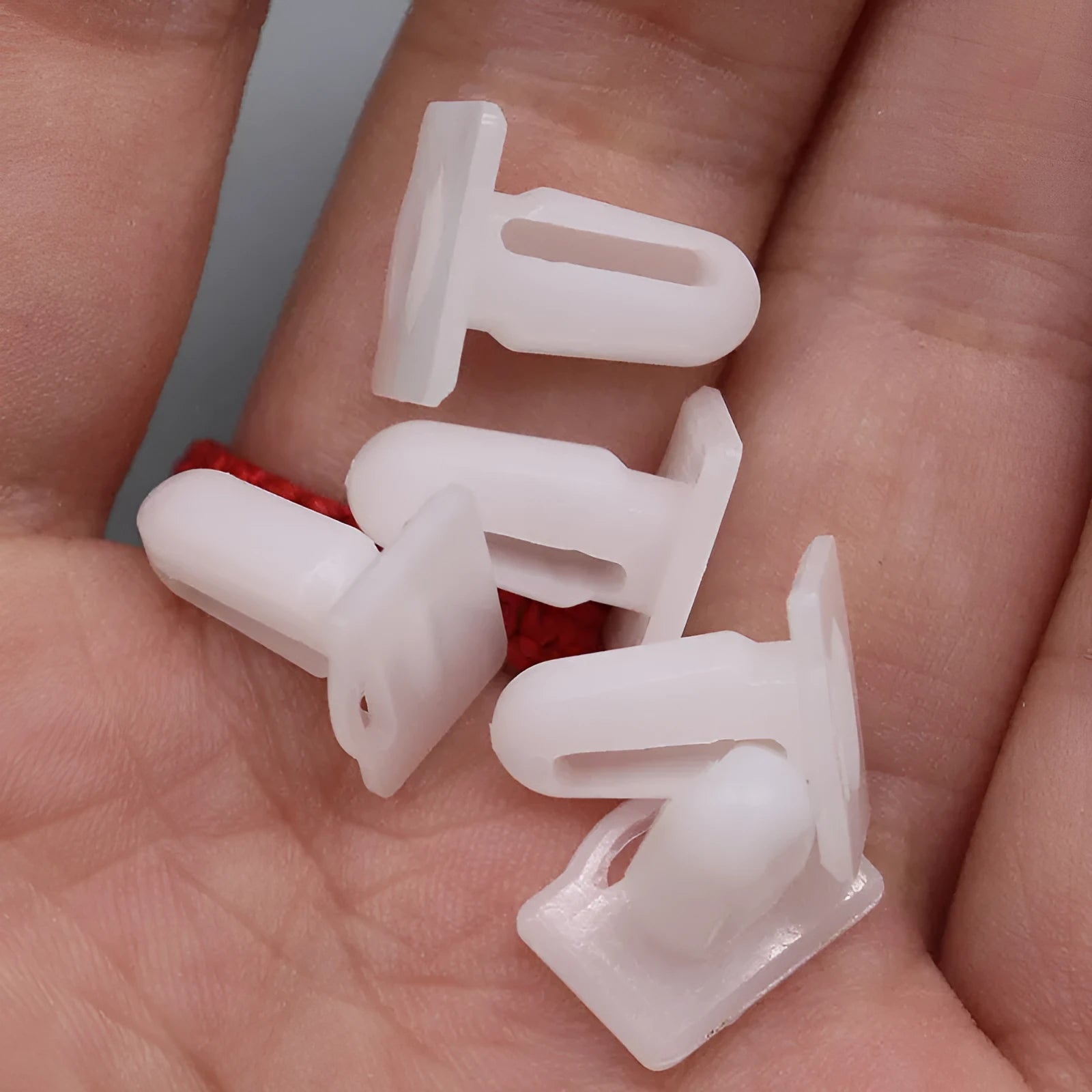 Sixty grey PA66 plastic car interior trim clips arranged on a white surface.