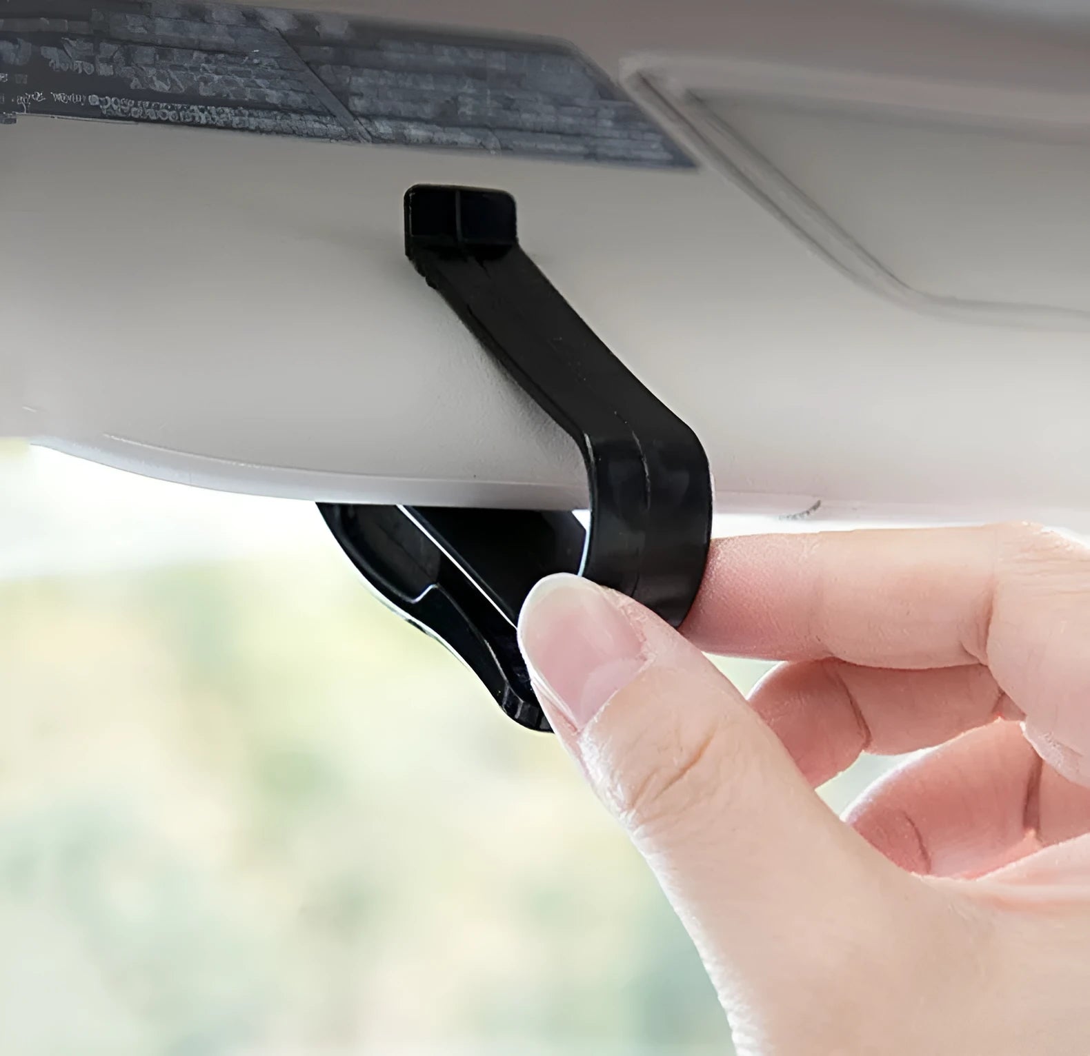Black plastic car sun visor clip holding a pair of sunglasses and a parking ticket.