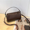 Vegetable tanned leather crossbody phone bag in cylindrical shape on a single adjustable strap.
