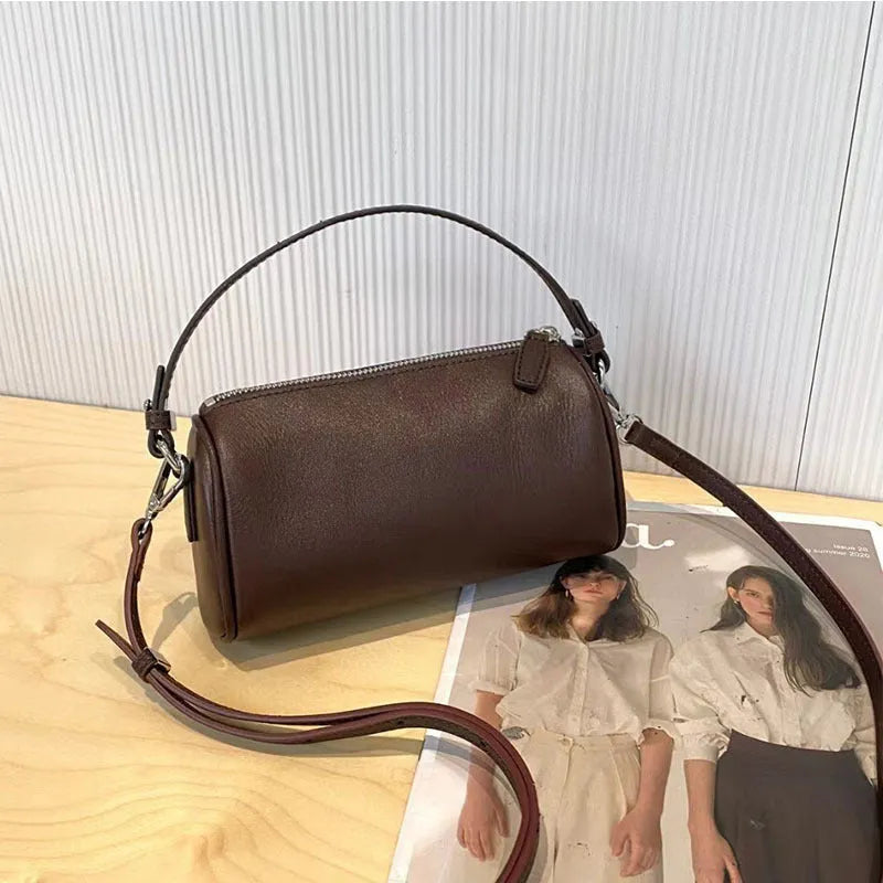 Vegetable tanned leather crossbody phone bag in cylindrical shape on a single adjustable strap.