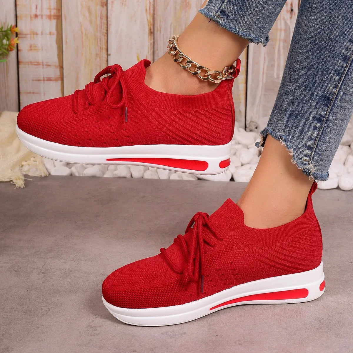 Women's red fly-knit lace-up sneakers with a low-top round-toe design on a white background.