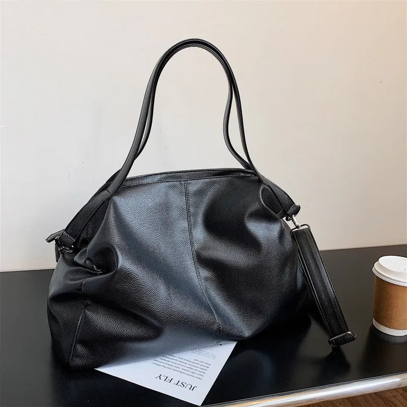 Large soft black PU leather messenger tote bag with a shoulder strap, showing zipper and phone pocket.