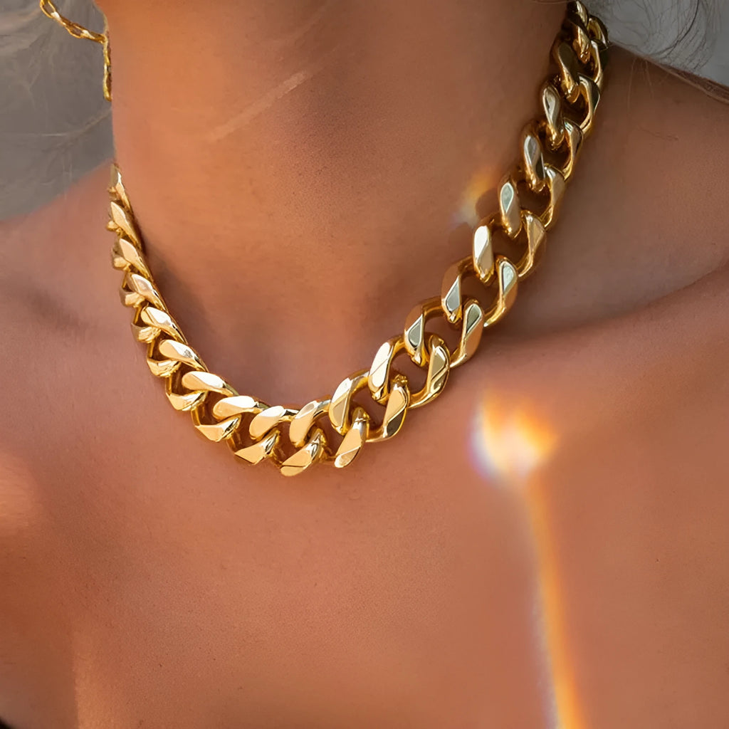 Gold women's thick chain necklace with 32cm length on a plain background.