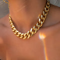 Gold women's thick chain necklace with 32cm length on a plain background.