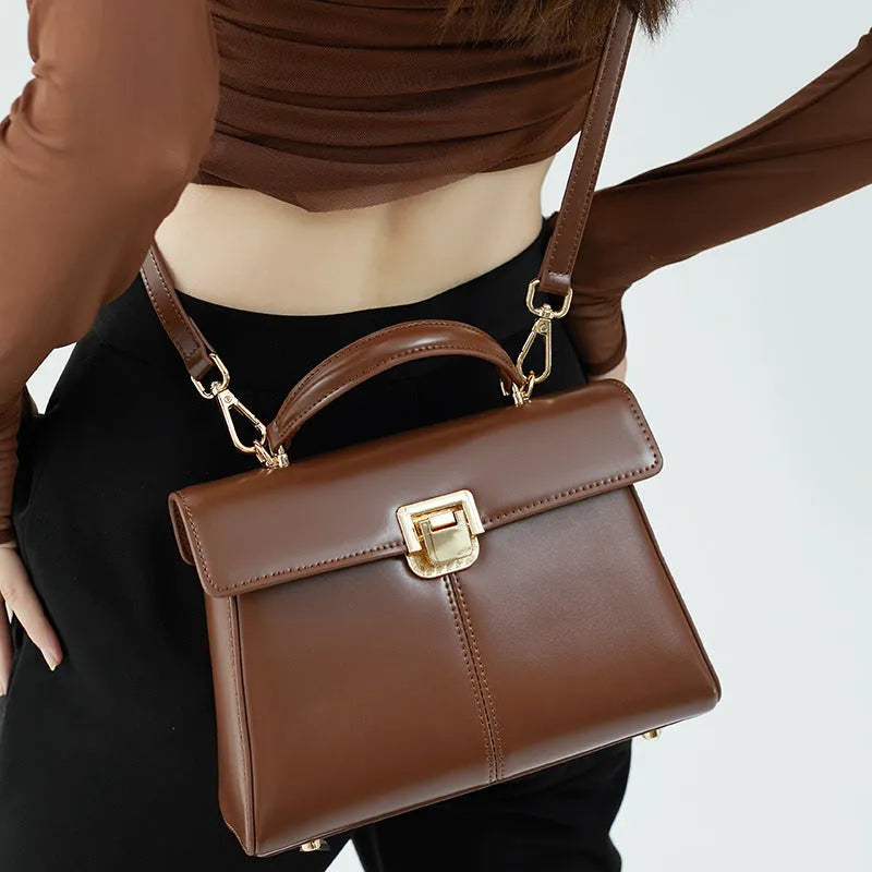 Black genuine leather women's shoulder bag with clasp closure showing square shape and adjustable strap