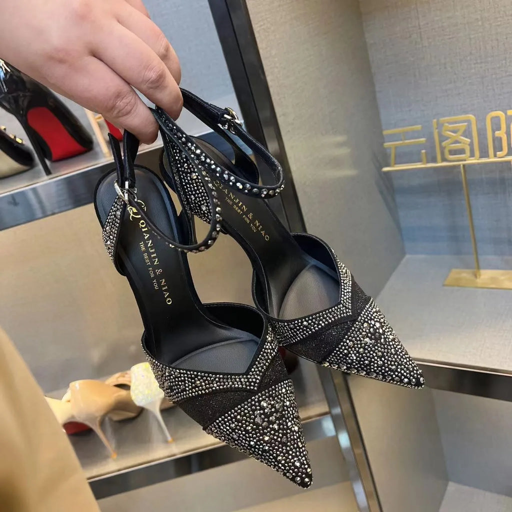 Black women's hollow high heels with pointed toe, stiletto heel, and red sole on a plain background.
