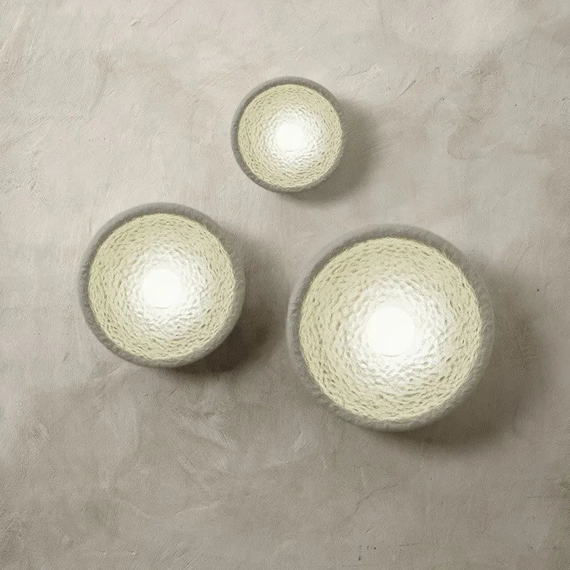 Japanese modern simple wall lamp with white resin shade in three size options on a plain wall.