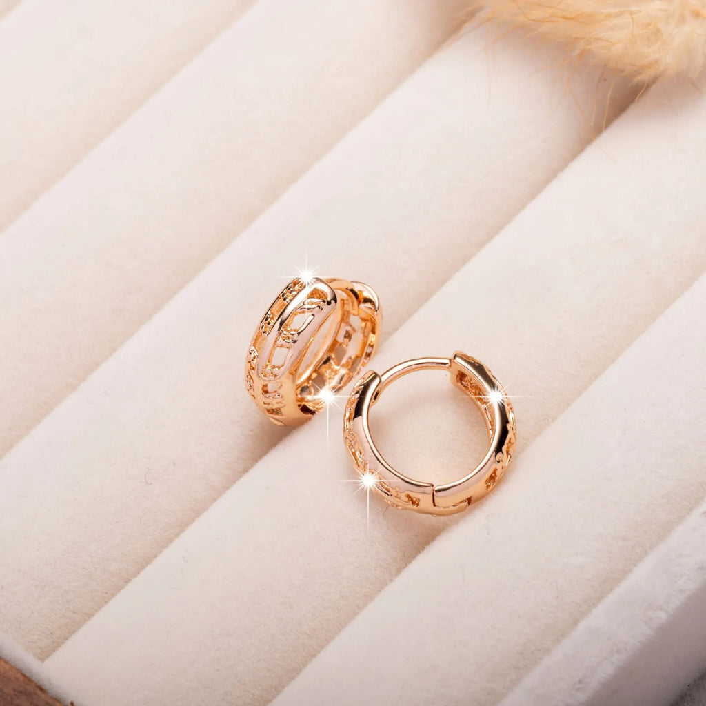 Rose gold coloured copper earrings with a hollowed leaf design and small heart detail.