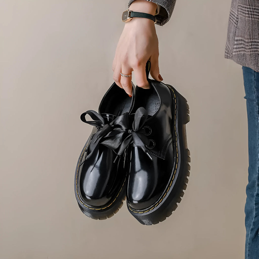 Women's black lace-up shoes with thick TPR sole, ribbon and cross strap details on superfine fibre upper.