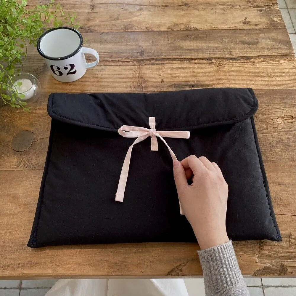 Women's black and white quilted nylon laptop bag with a ballet-style bow.