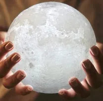 3D printed white moon lamp on a wooden stand, showing detailed craters and soft LED glow.