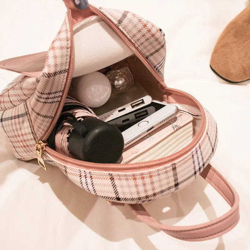 A black diagonal one-shoulder phone bag made from PU fabric, shown being carried by hand.