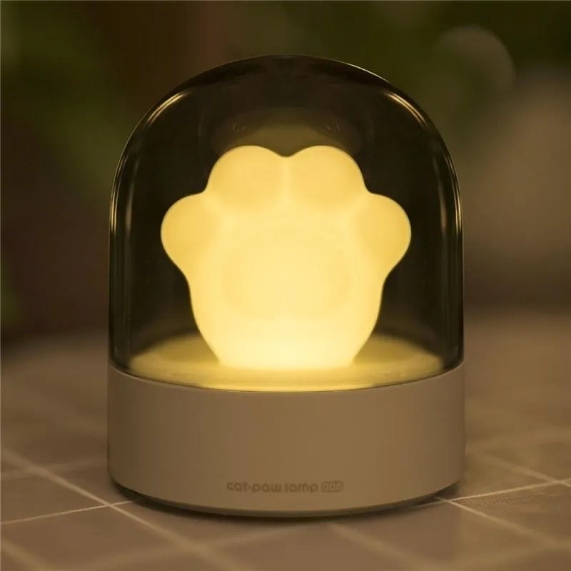 Pink cat paw shaped USB rechargeable night light with musical box function on wooden desktop