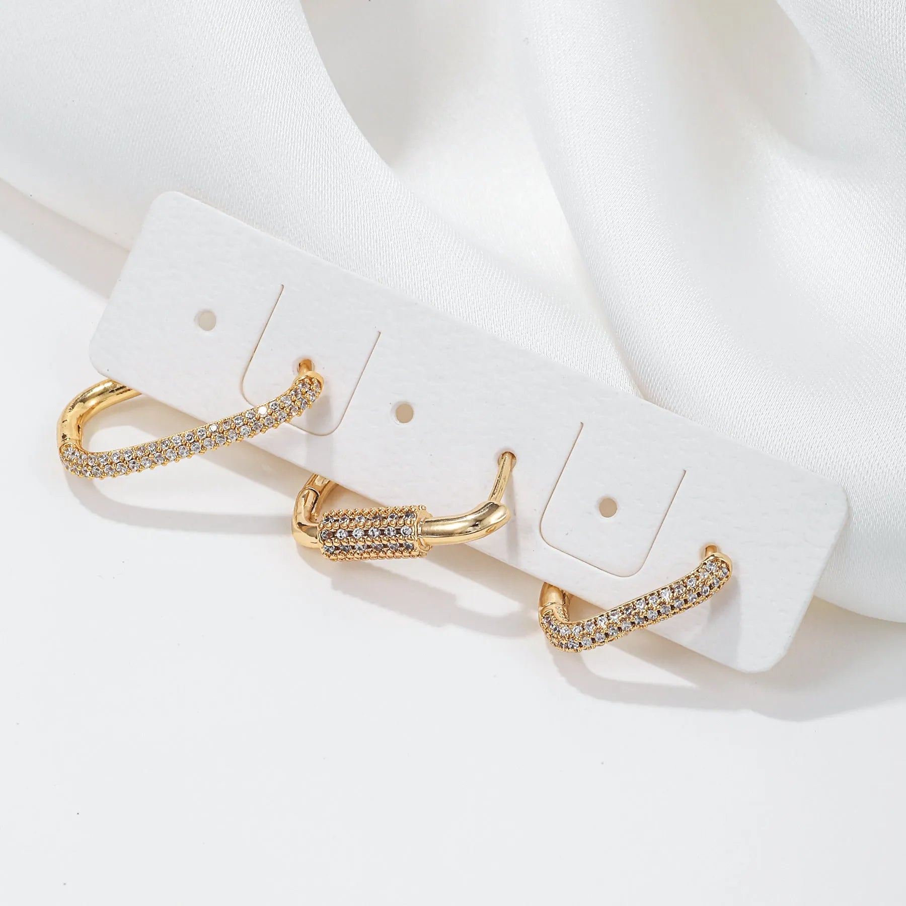 Three geometric square ear clips with inlaid zircon stones in gold and white gold colours