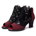 Black women's gladiator sandals with lace upper, square high heel, and side zip closure on a foot.